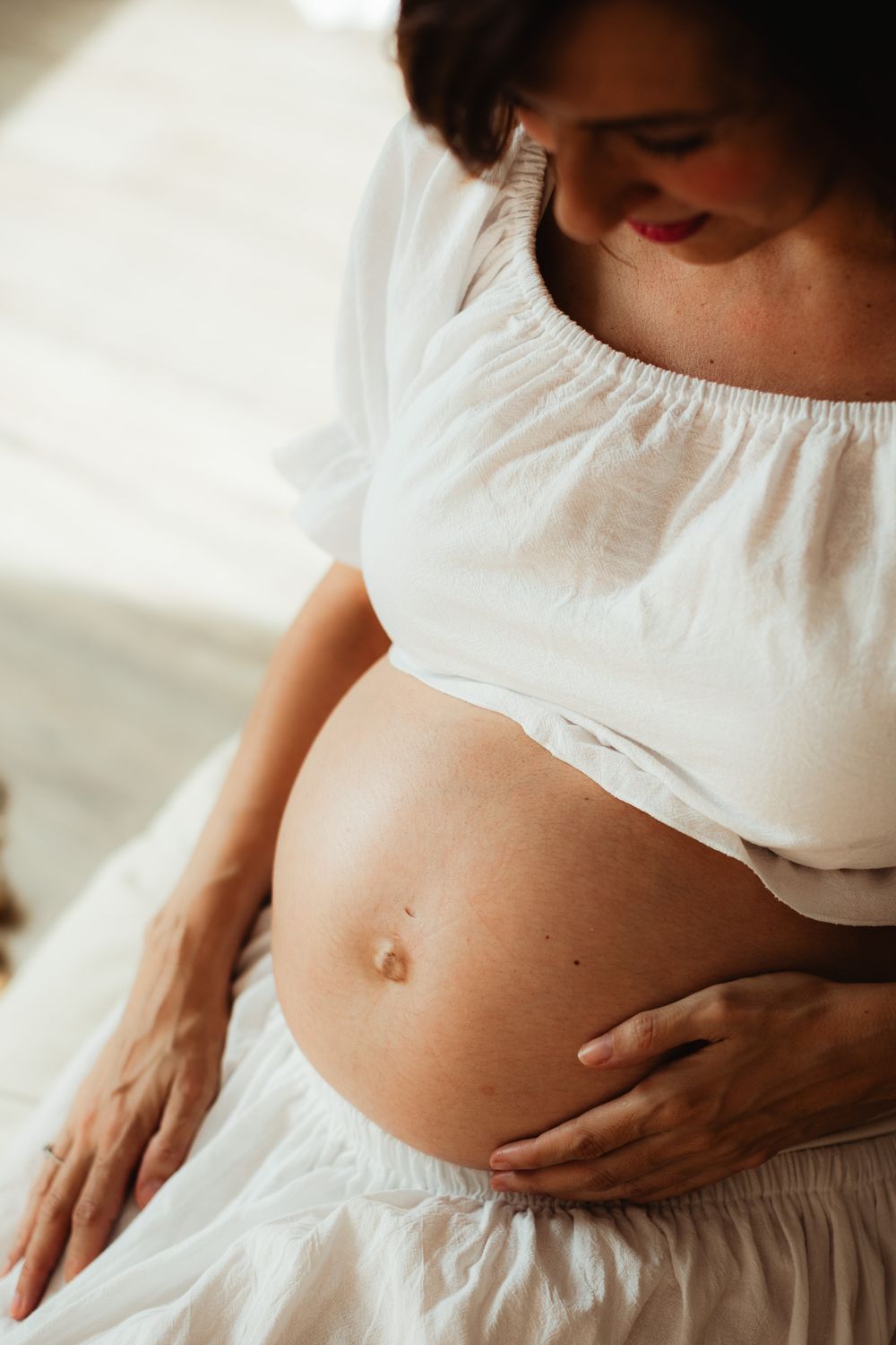 Close-up view of a pregnant belly in white clothing showing the progression of pregnancy growth across multiple frames.