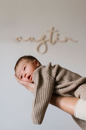 Artistic series of baby in beige knit sweater against neutral background.