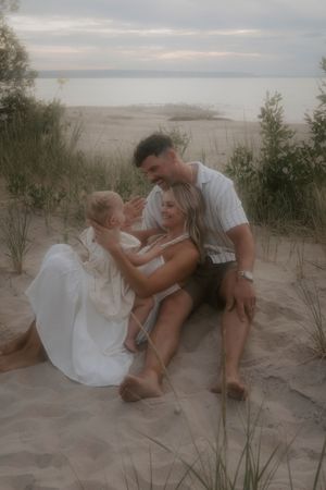 A family shares playful moments together on sandy dunes at sunset.