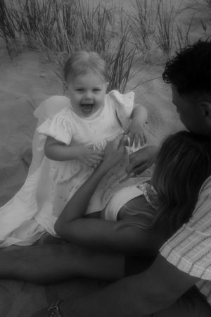 Black and white photo of a family playing and laughing together on a beach.