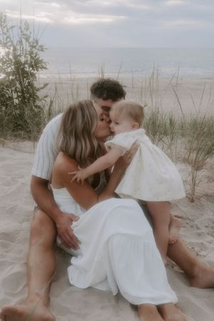 Family shares tender moments together on beach sand dunes.