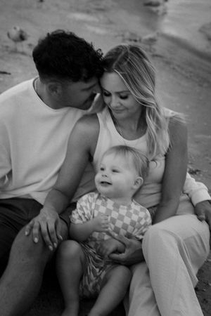 A tender black and white family portrait showing intimate moments between parents and their young child.