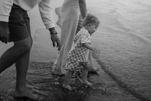 Black and white image of splashing feet in shallow beach water.