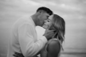 An intimate black and white portrait of a couple sharing a romantic moment at sunset.