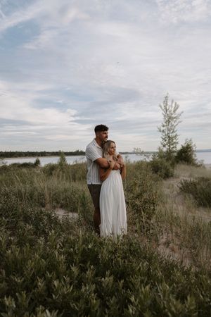 Couple embracing on a coastal path surrounded by natural vegetation.
