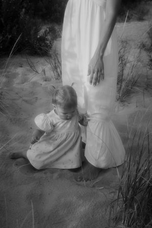 Black and white image of figures in white clothing on sandy ground.