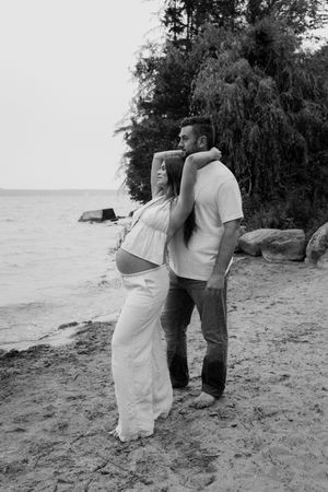 Black and white photo of a couple sharing tender moments on a beach.