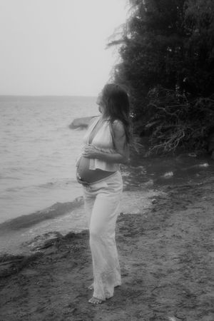 Artistic black and white beach maternity photos with waves in the background.