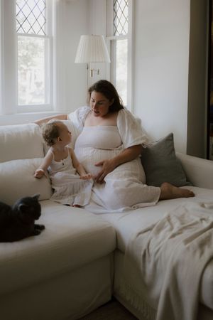 Candid moments captured on a light gray couch near a window with diamond panes.