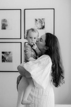 Intimate black and white portraits of parent and baby playing together against gallery wall.