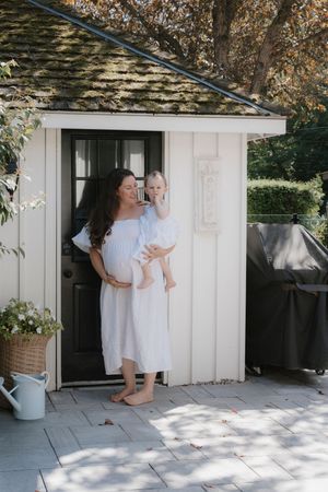 Family in white dresses sharing playful moments outside a white building on a sunny day.