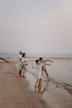 Family playing and splashing in ocean waves at beach during sunset.