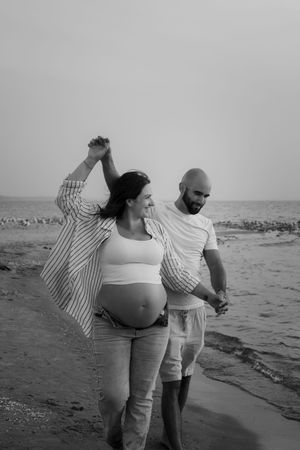 Black and white beach photos of couple enjoying sunset with waves in background.