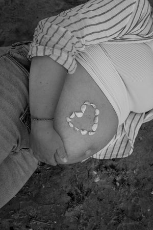 Black and white photo series showing pregnancy progress with heart-shaped stickers marking monthly growth.