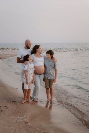 Family walking together on beach at sunset with waves in background.