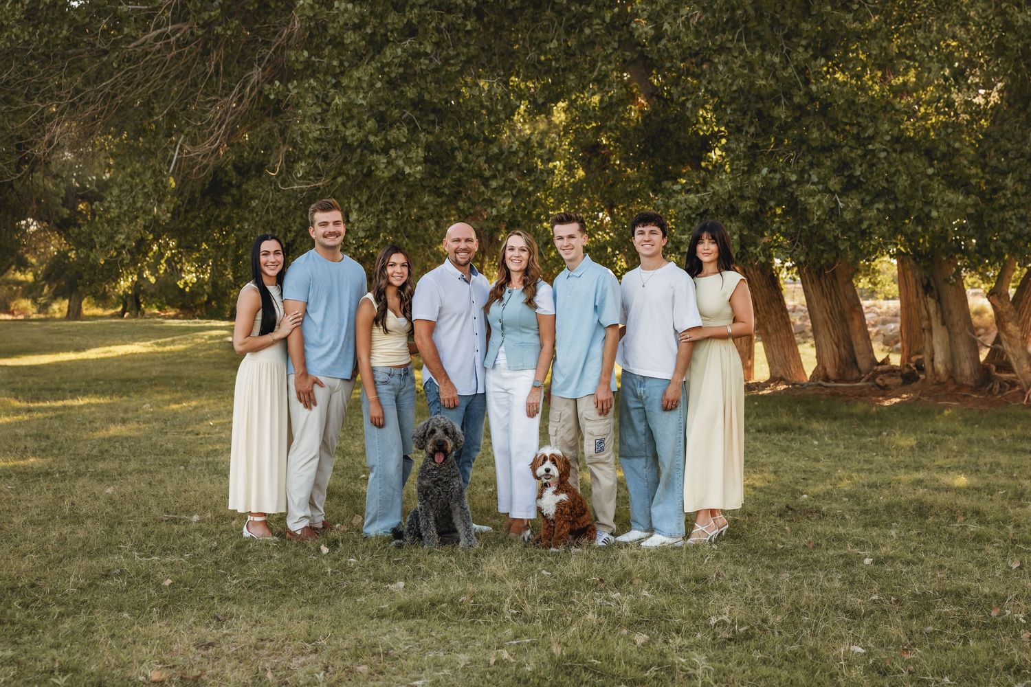 Group photo of extended family with sunlight streaming through trees.