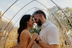 A romantic couple shares an intimate moment in front of a twinkling light backdrop.