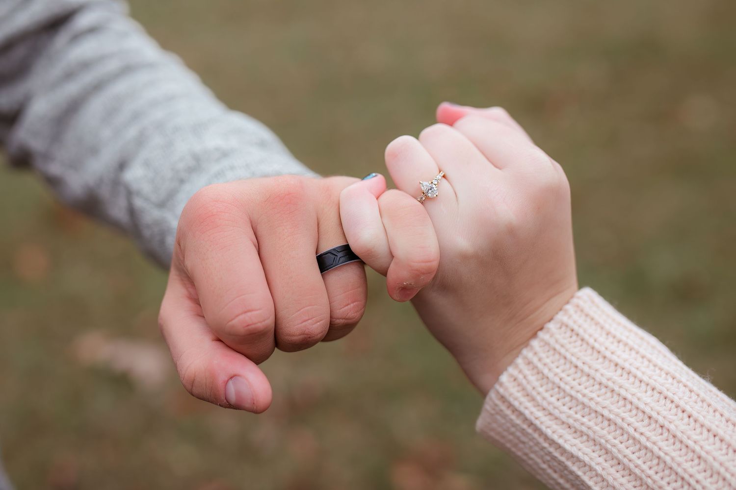 Close up of two hands with wedding rings making a pinky promise gesture.