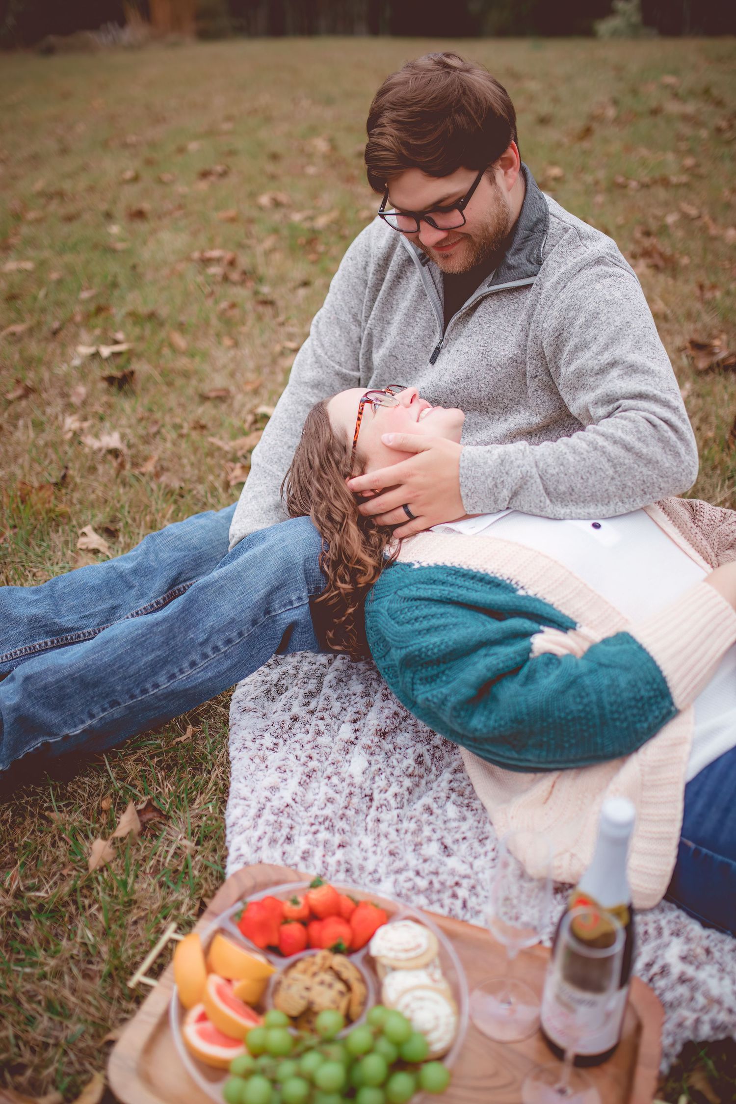Couple sharing intimate moment during autumn picnic with fresh fruits and wine.