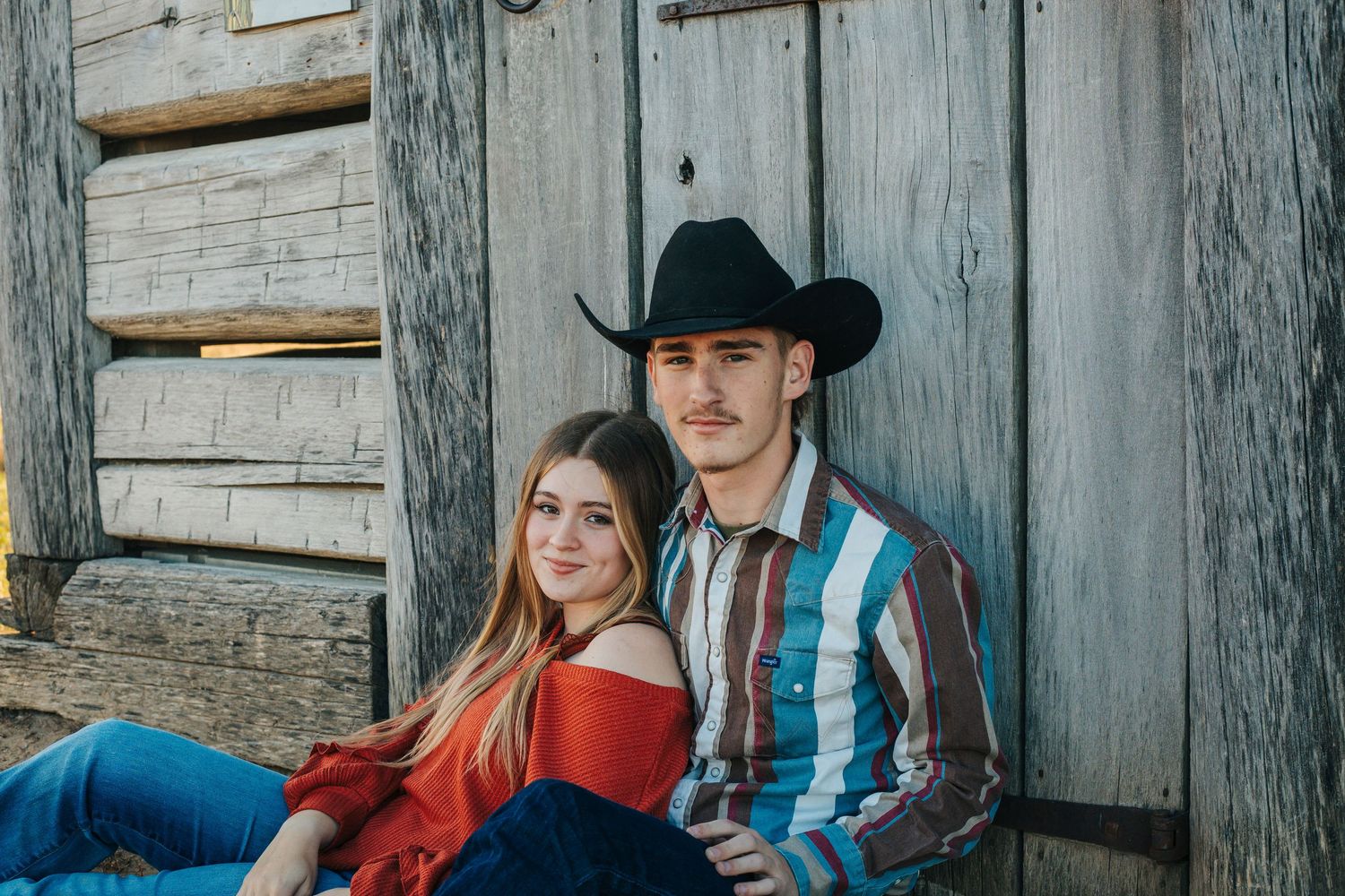 Casual portrait session against metal siding backdrop on grassy area.