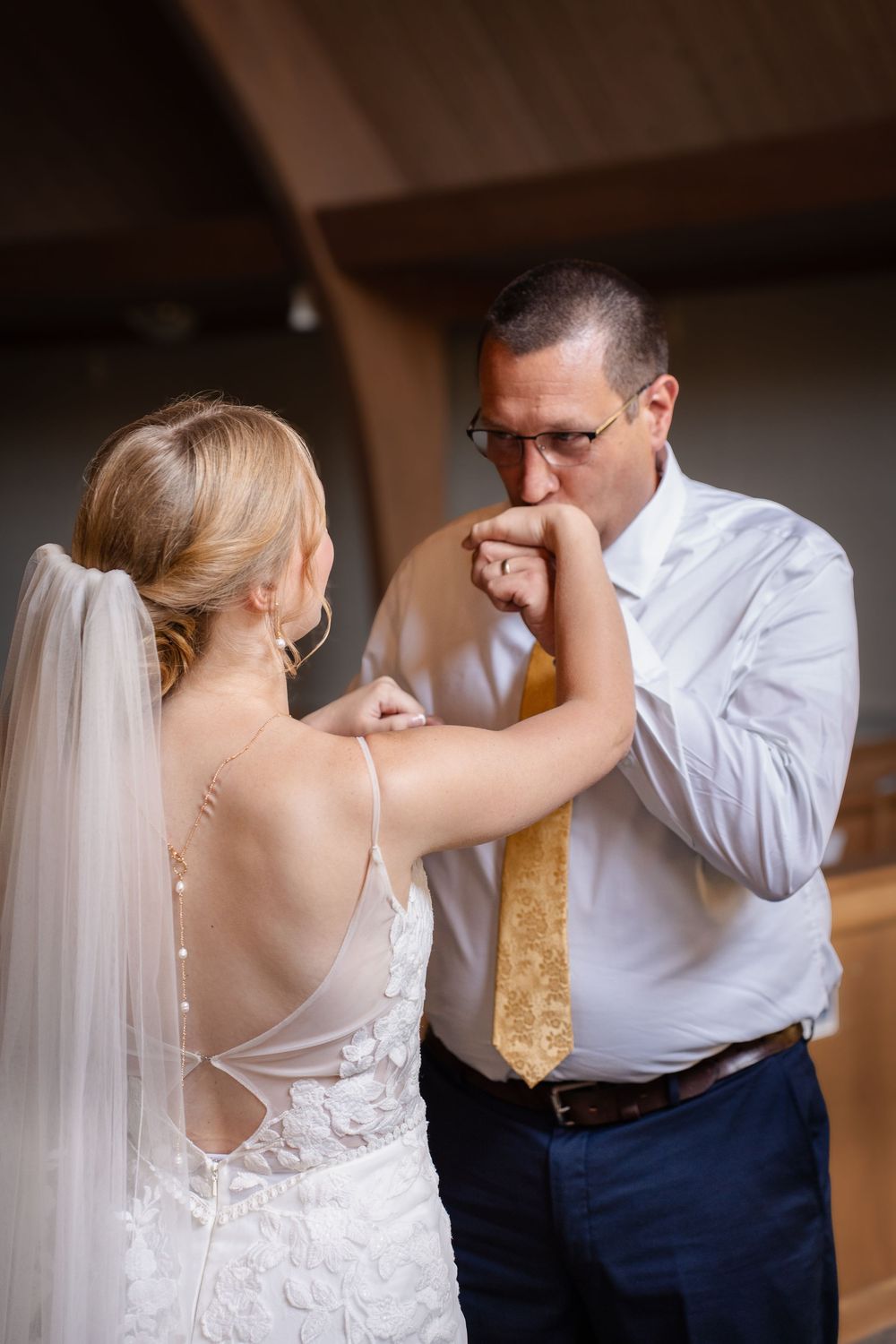 A tender moment between newlyweds as groom kisses bride's hand during wedding ceremony.
