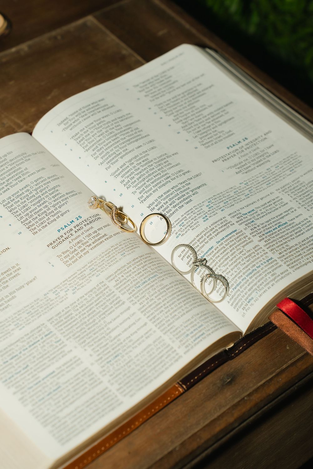 Wedding rings resting on open Bible pages showing Psalms, placed on rustic wooden table.