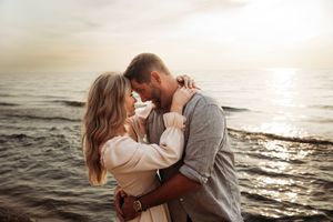 Romantic couple embracing near the ocean shore during a breathtaking golden sunset.