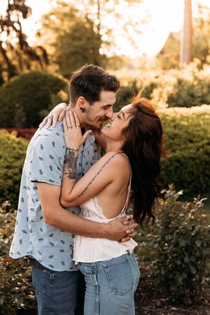 Couple sharing a romantic almost-kiss embrace in a sunlit garden.