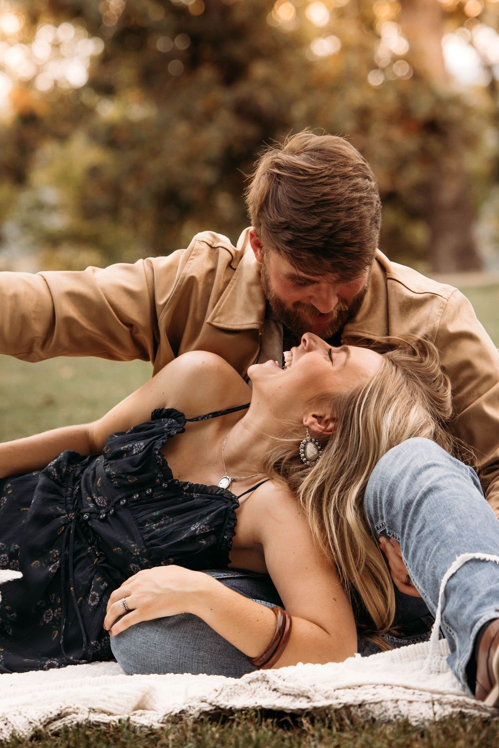 Couple sharing a tender moment on a blanket in an autumn park.