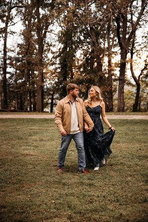Couple holding hands and walking through a sunlit autumn park.