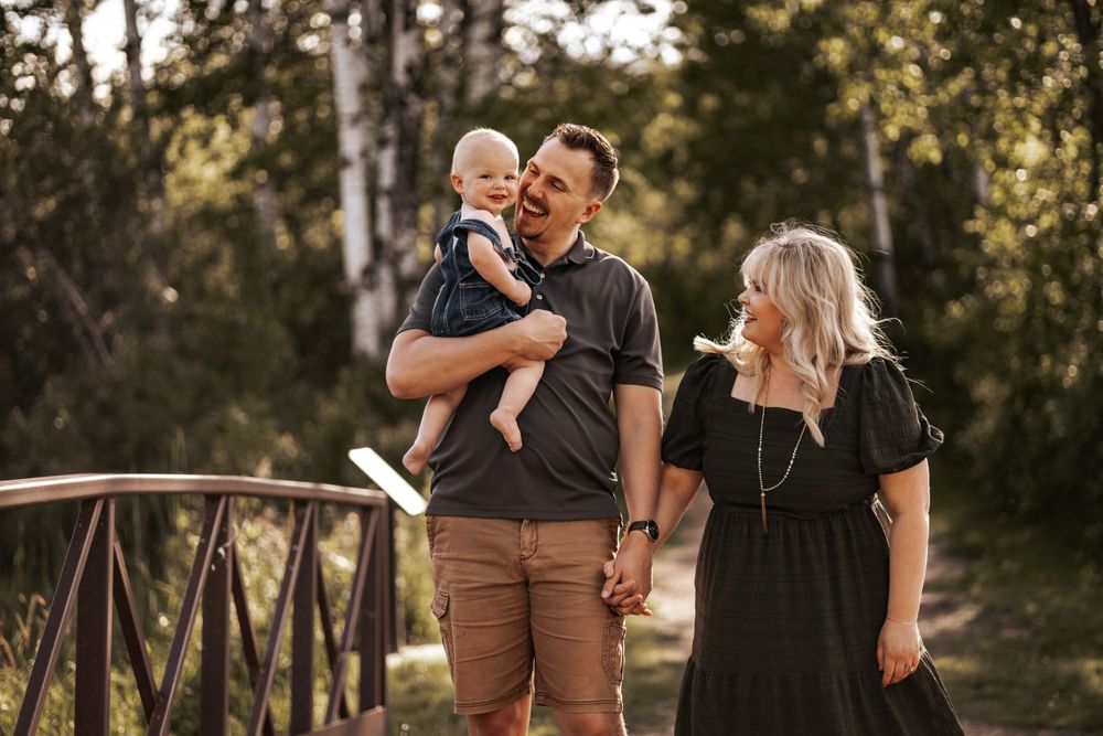 Family enjoying outdoor moment together on wooden bridge in nature setting.