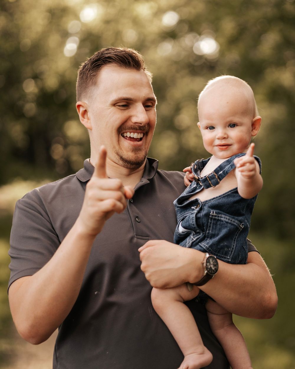 Joyful outdoor family moment with baby in overalls.