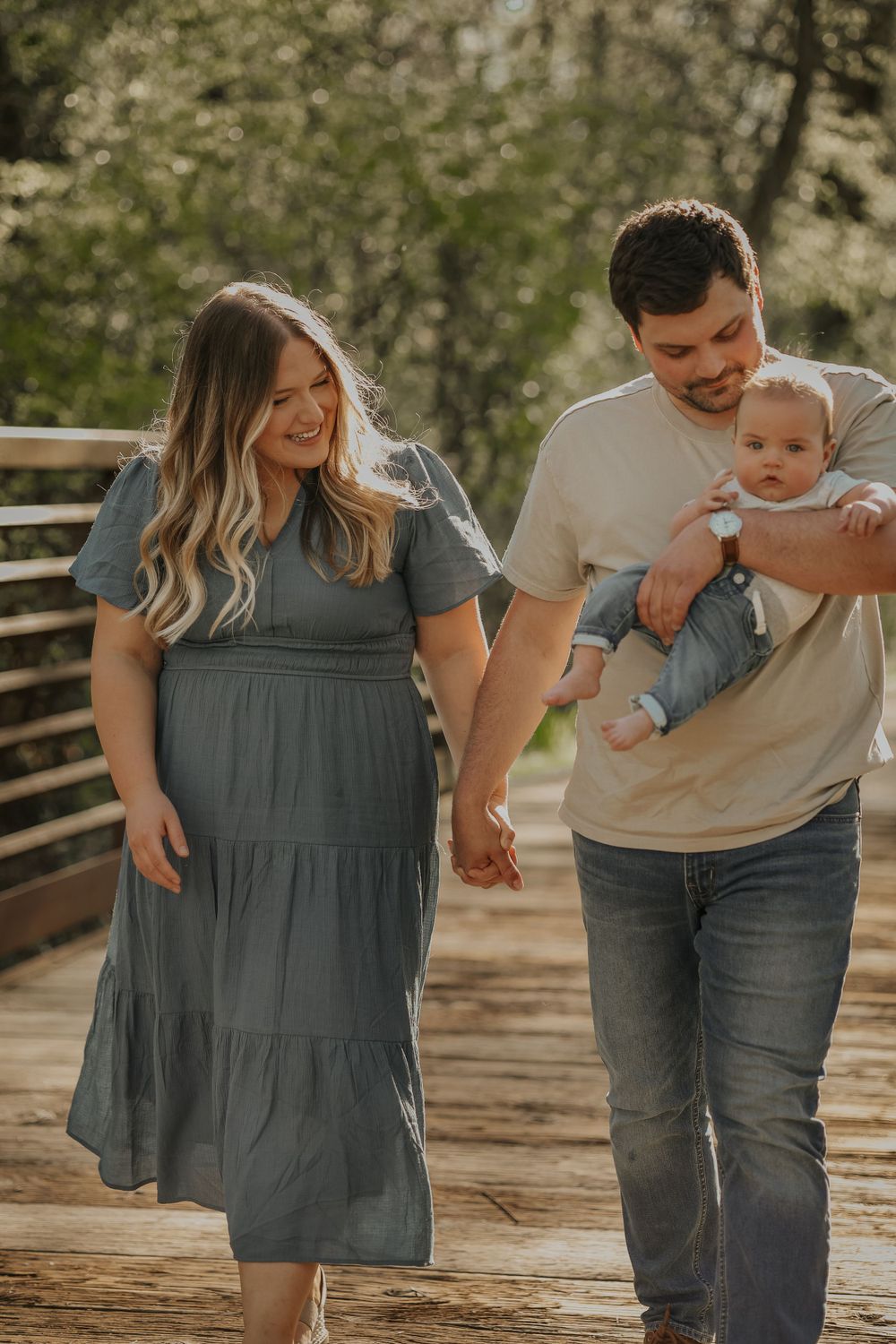 Family walking together on wooden bridge during sunset photoshoot.