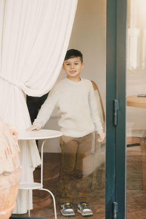 Young man standing in a bright doorway during a casual senior portrait session.