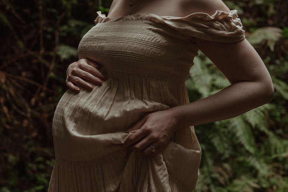 Side view of pregnant belly in textured dress against natural outdoor setting. PNW Maternity Photographer. Portland Photographer