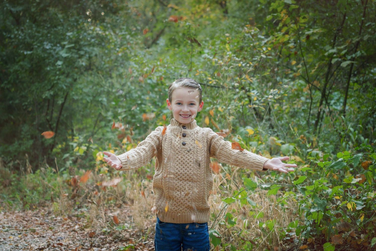 portrait photography Fall family mini session fall colors family love boy throwing orange leaves fun childhood outdoors