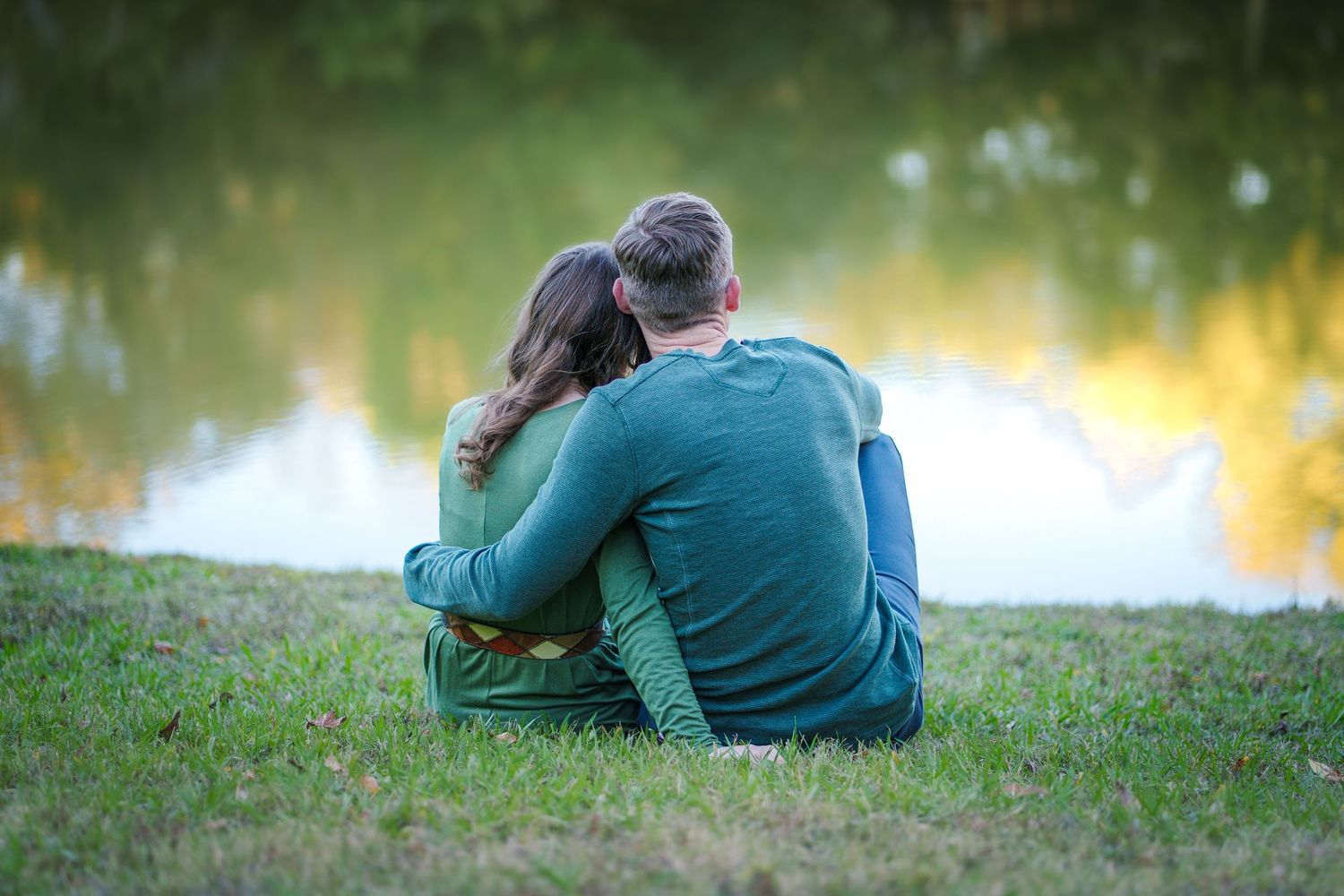 Fall family session mini Colleyville Texas mom and dad love sitting by the ponds giving backs to camera hugging parents fun telling secrets