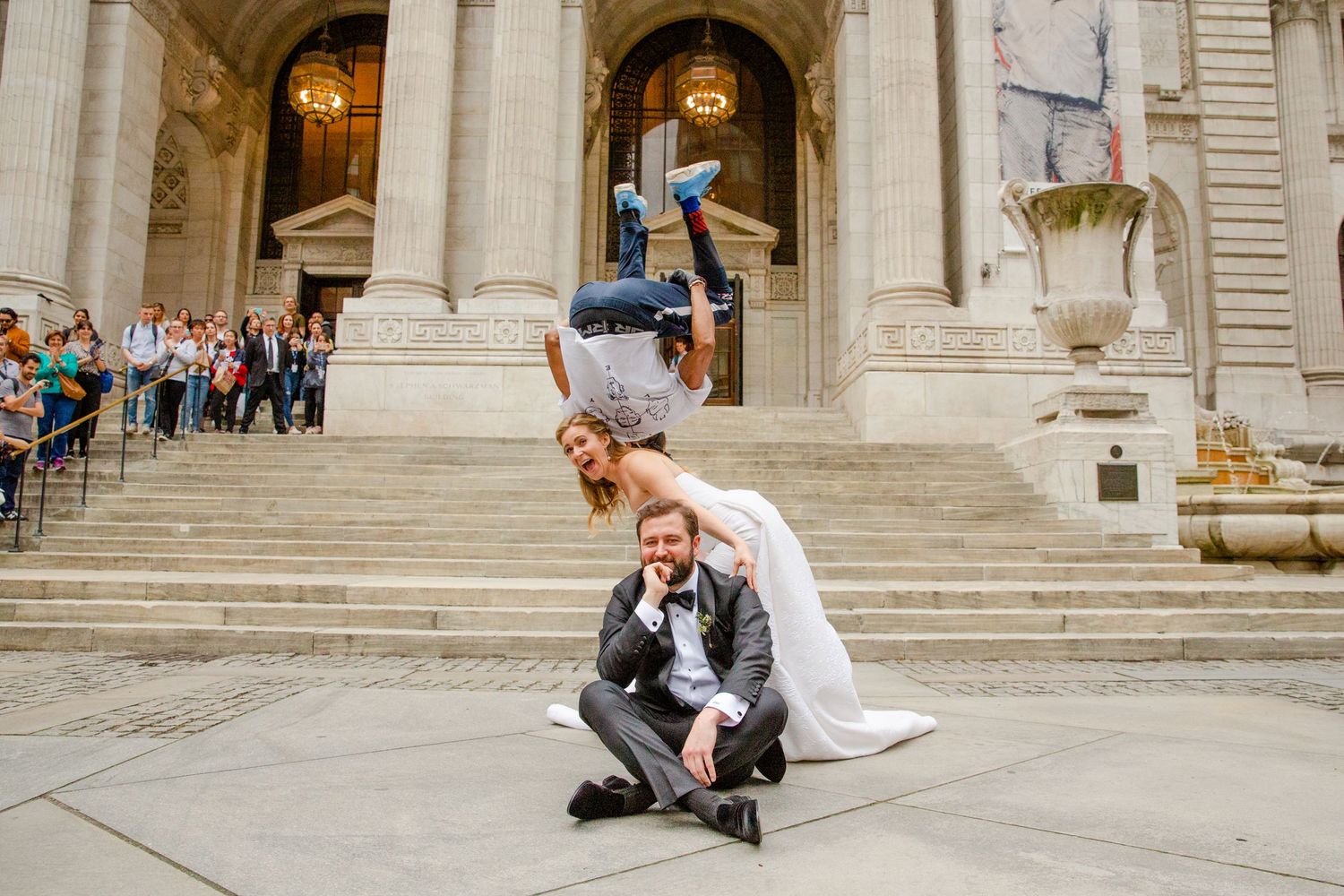 An acrobatic wedding pose shows a couple performing a dramatic lift on grand stone steps.