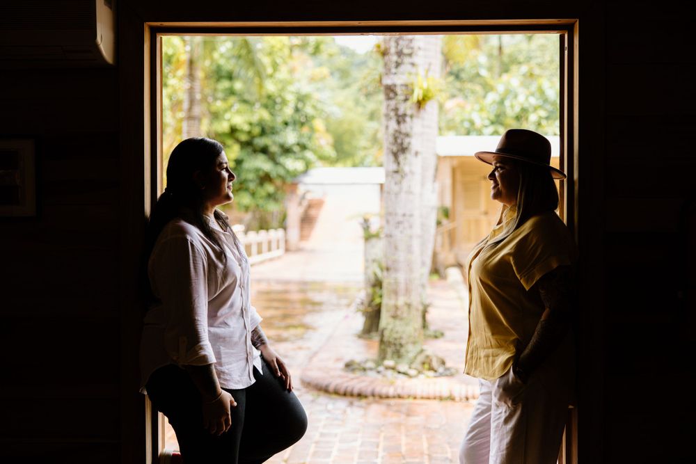 Two silhouettes framed in a doorway with sunlit garden visible behind them.