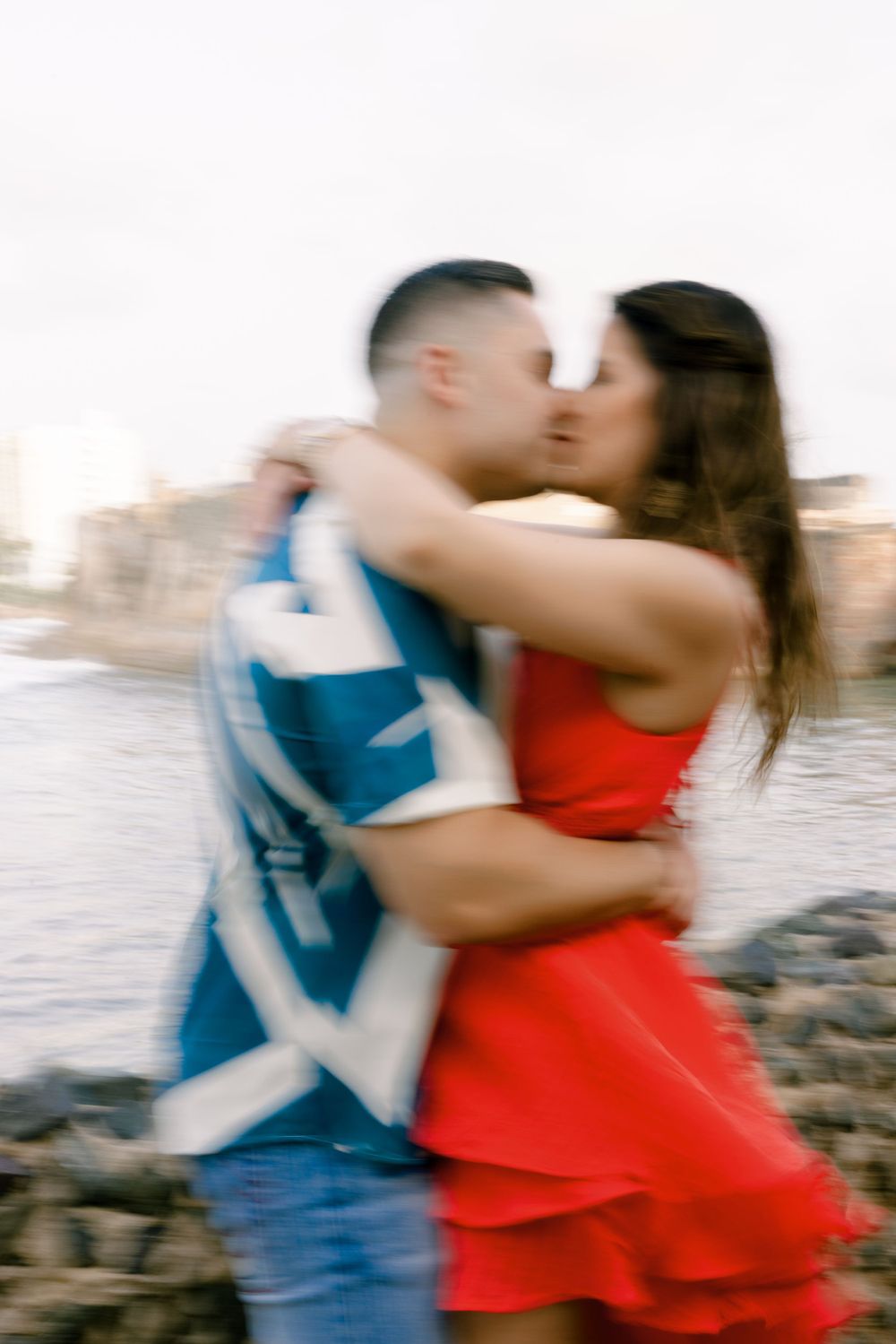 A blurred motion romantic embrace captured against coastal backdrop.