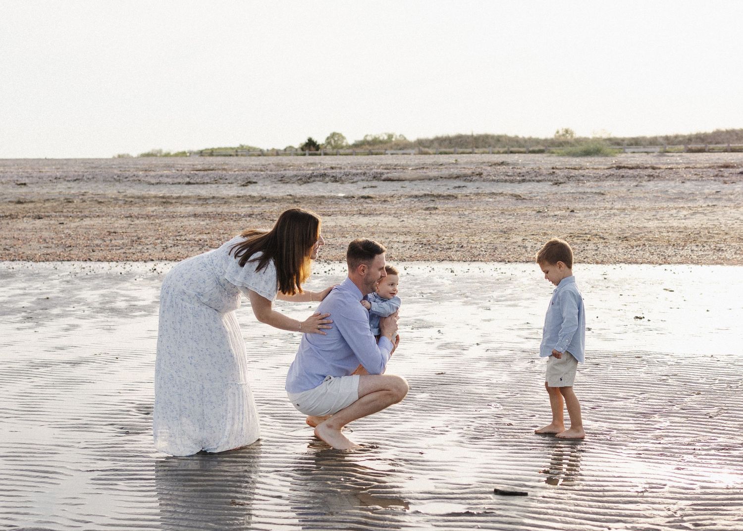 Family enjoying playful moments together on a sunny beach.