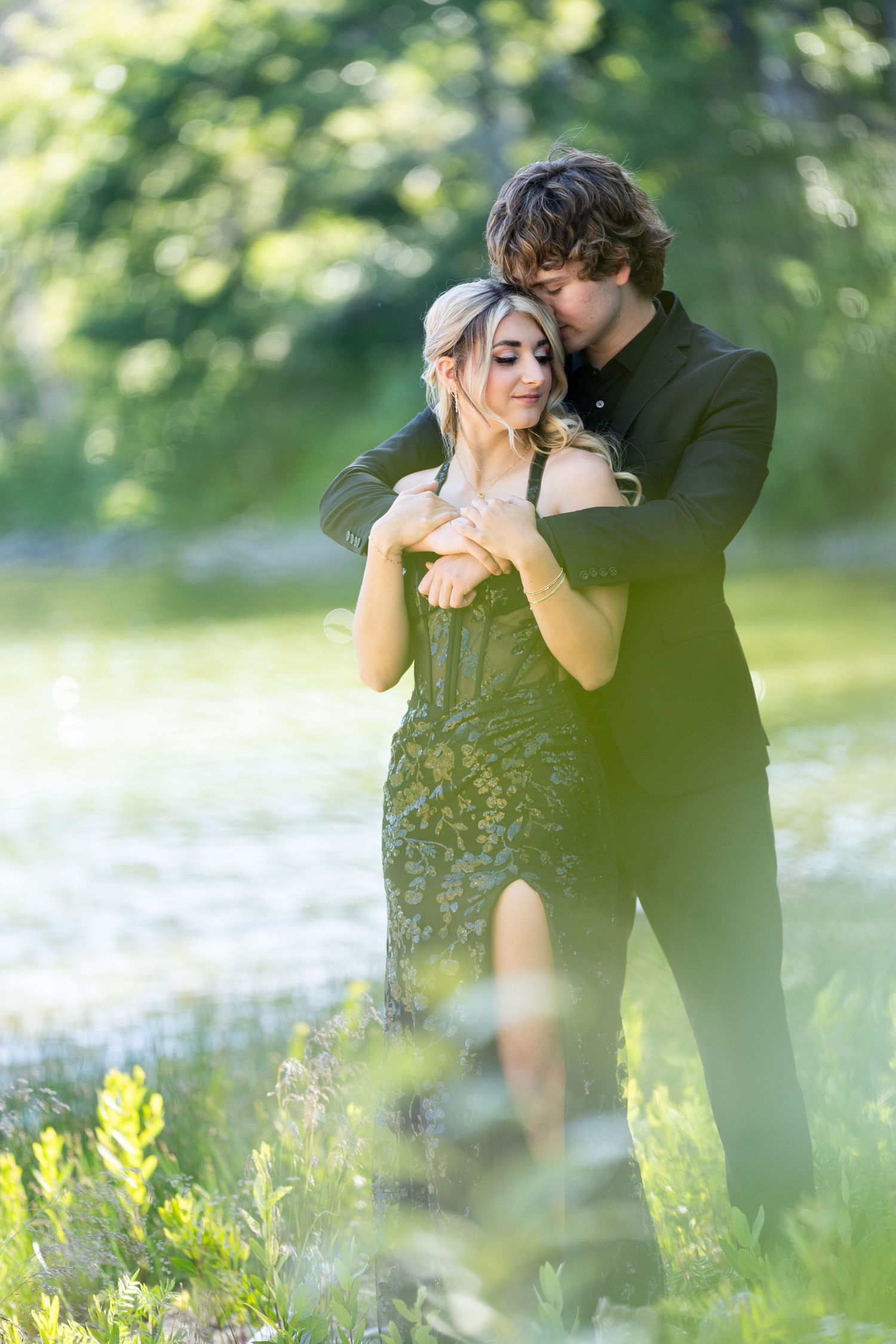A couple embraces romantically in a sunlit meadow filled with wildflowers during a spring photo session.