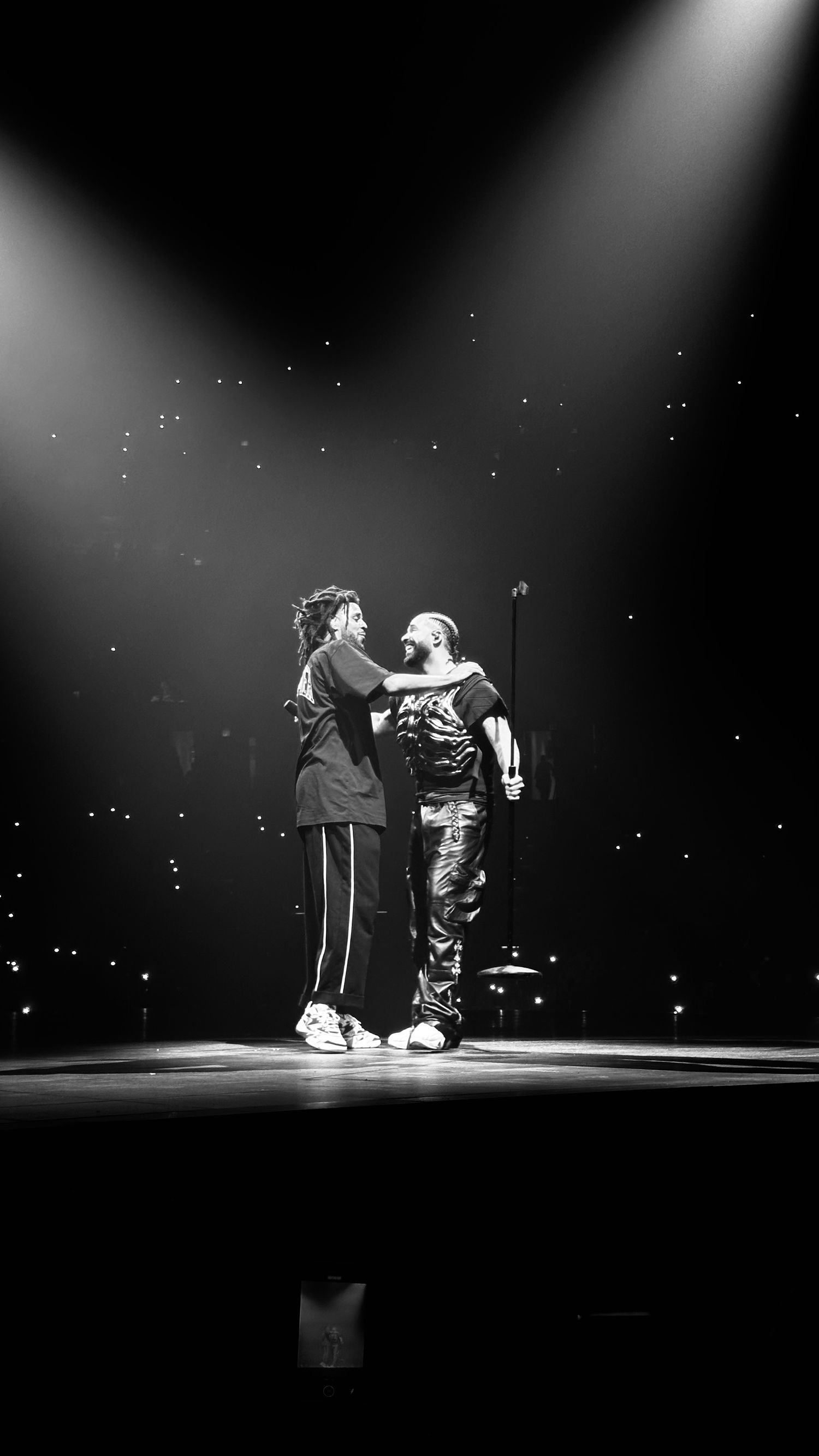Performers on stage under dramatic spotlights in black and white.