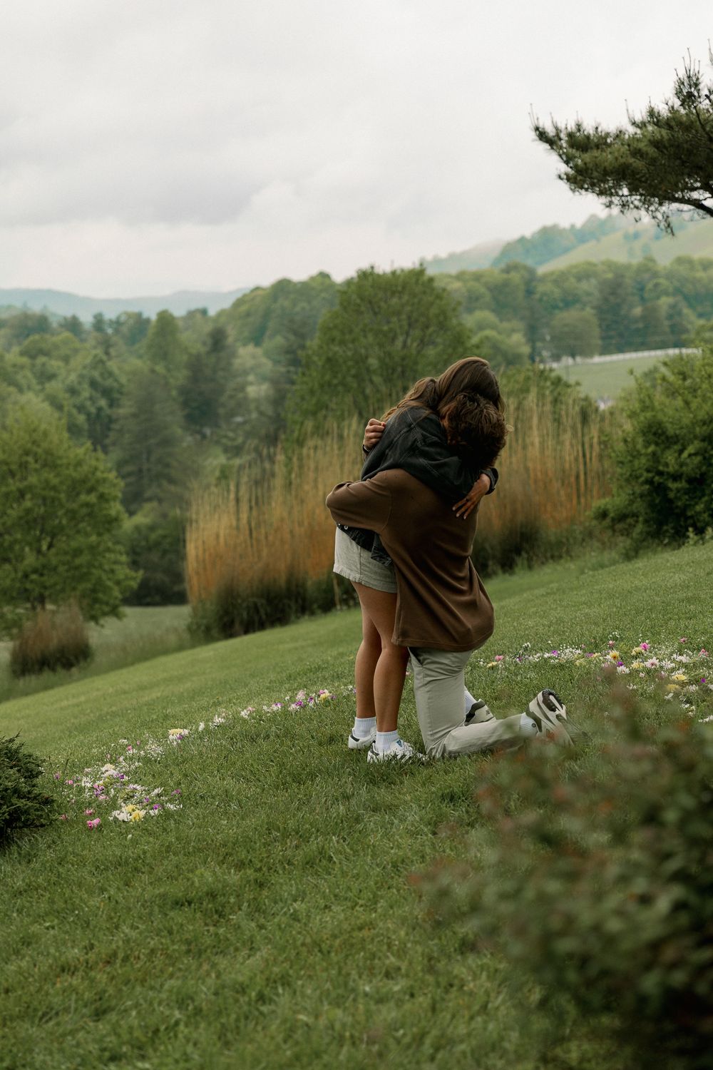 Photographer capturing shots on a grassy hillside with mountain views.
