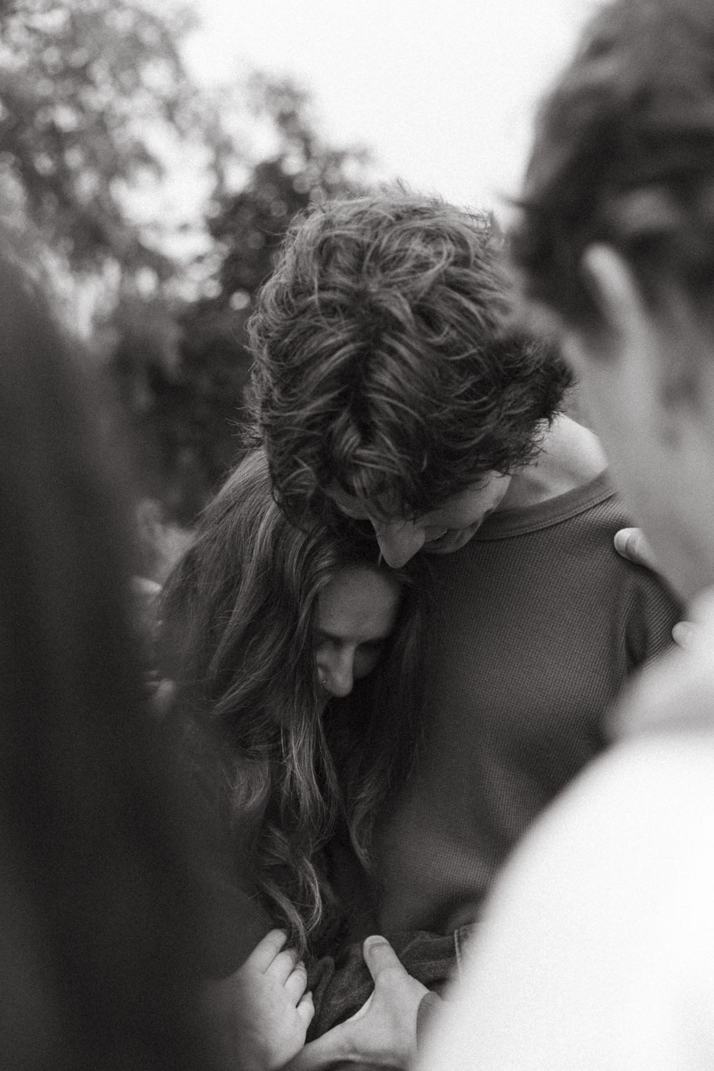 An intimate black and white moment captured between a couple embracing outdoors.