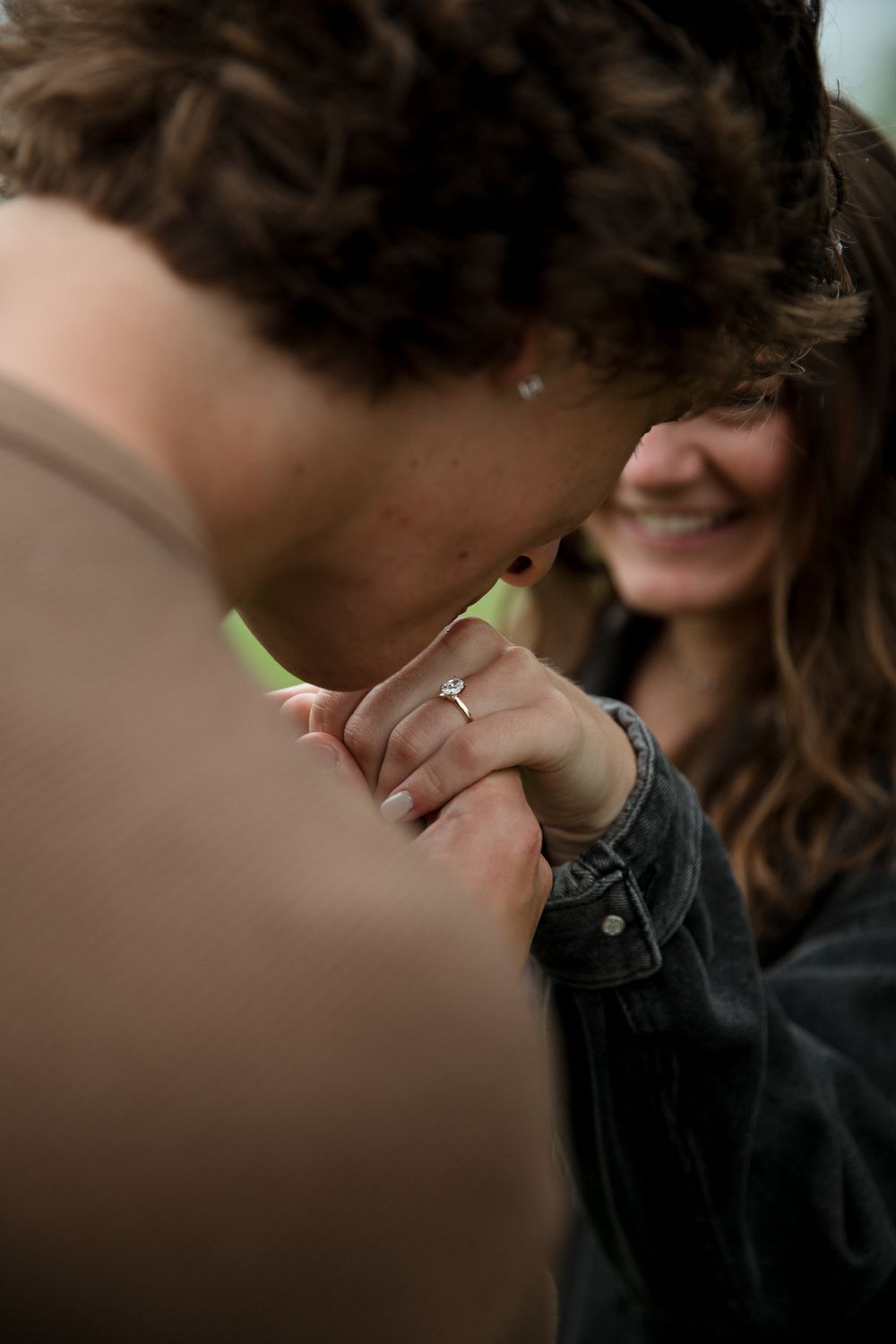 Close-up shot showing hands with an engagement ring during an intimate moment.