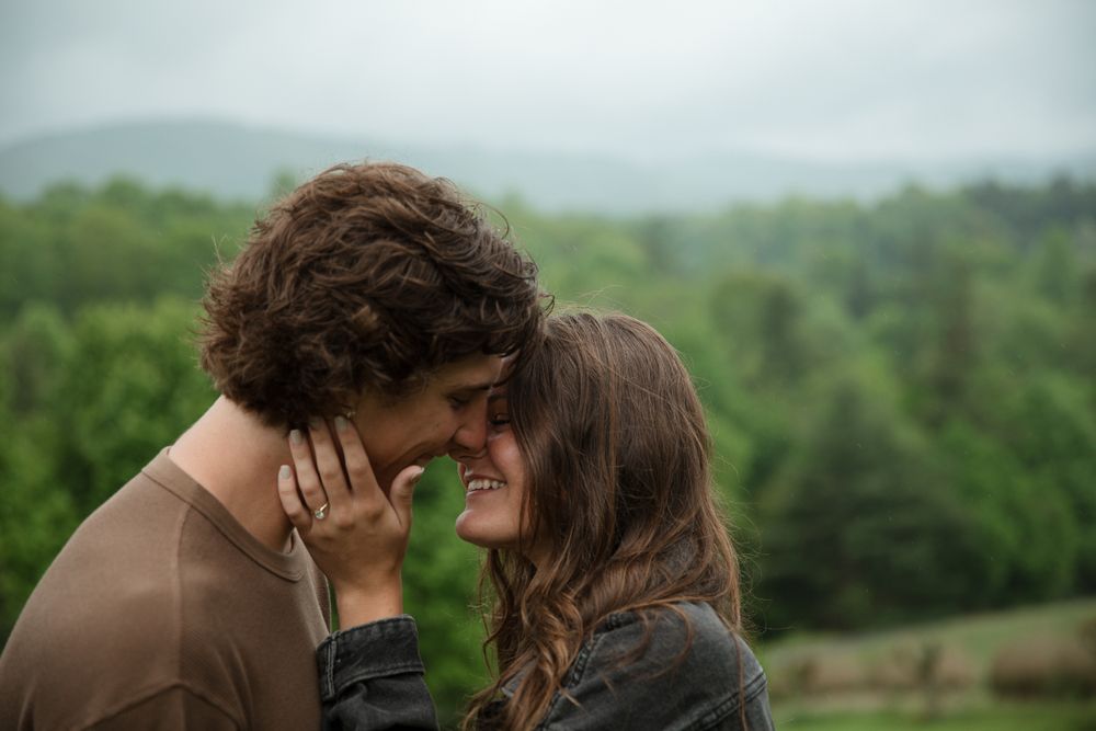 A romantic moment shared between a couple against a backdrop of rolling green hills.