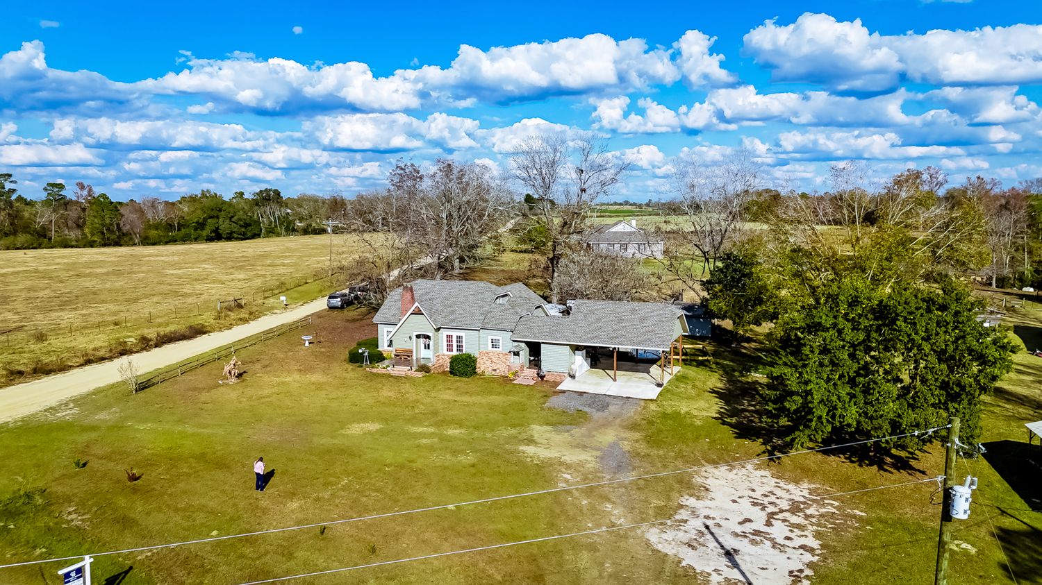 Panoramic drone shot of rural property with buildings and open fields.