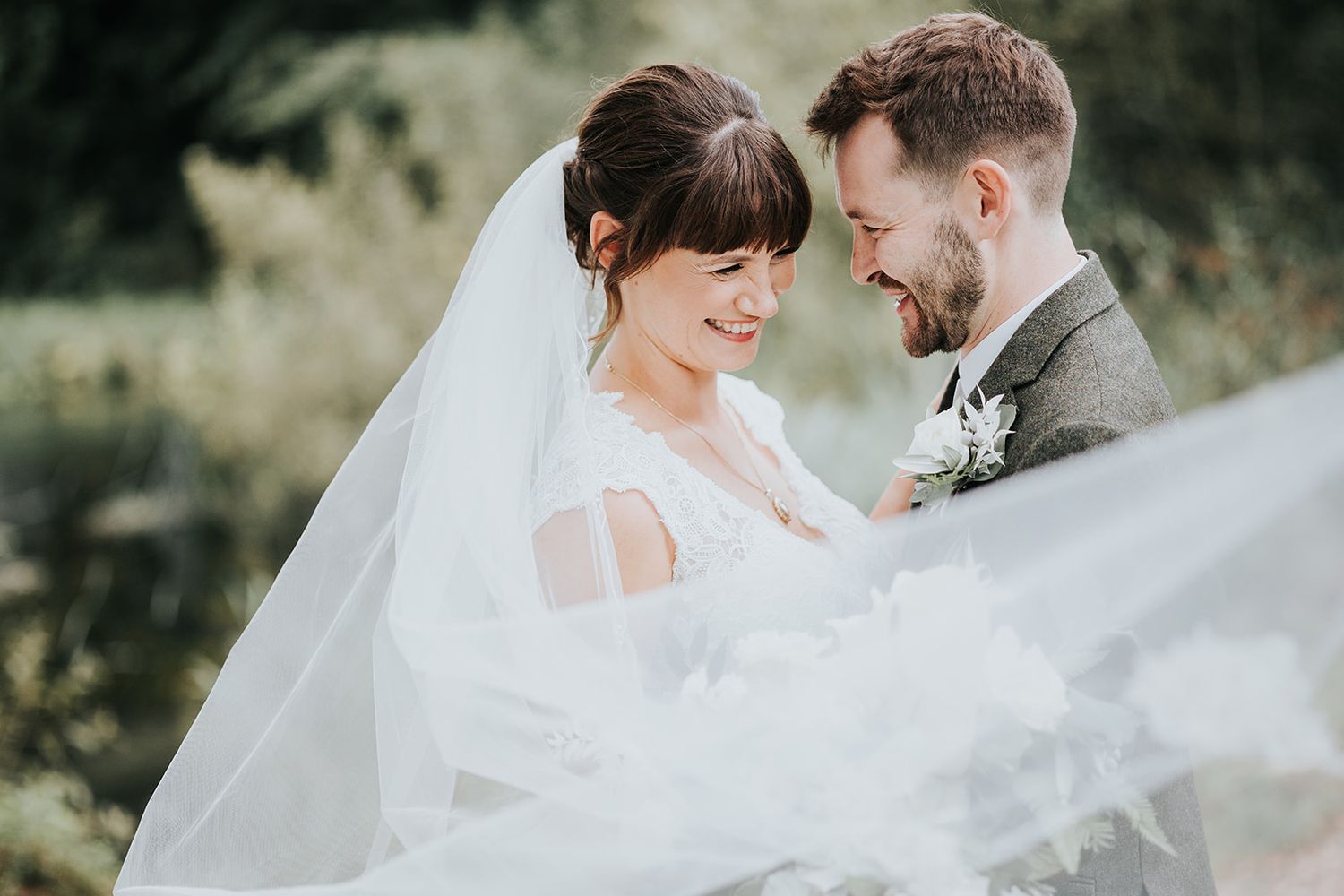 A romantic wedding moment captured with flowing veil and natural outdoor backdrop.