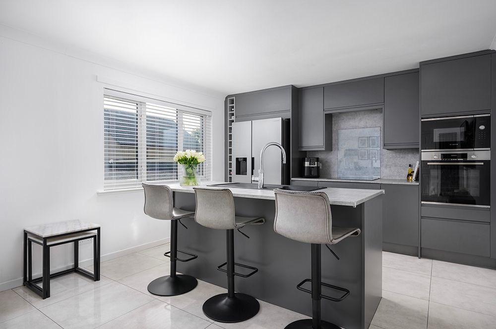 Modern minimalist kitchen and dining space with white and gray color scheme featuring sleek furniture and clean lines.